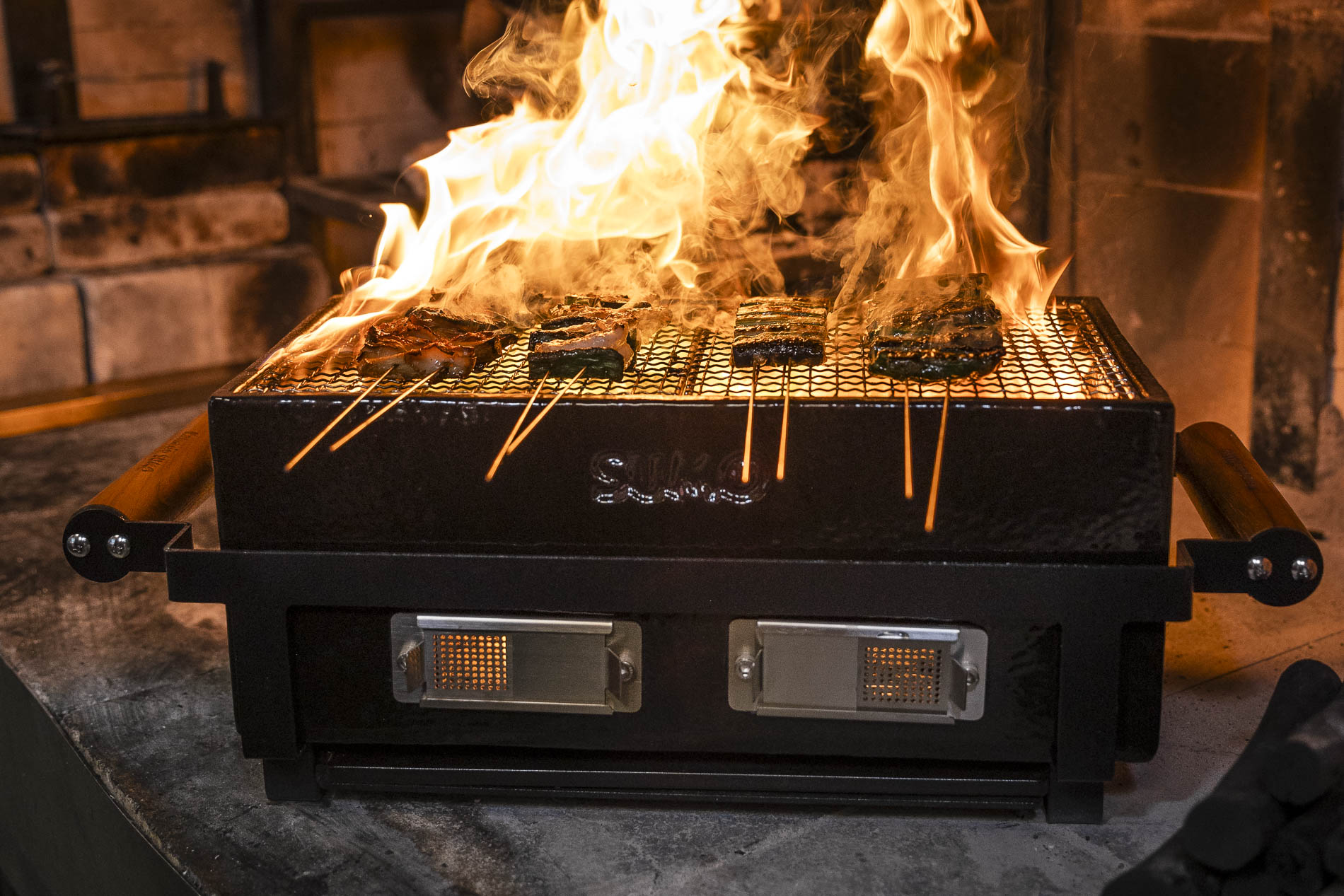 Kamado sumo Hibachi grill med flammande eld som grillar grönsaker.
